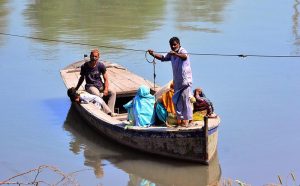Women with their kids cross the Channel Mori Canal by boat, navigating daily life in the city.