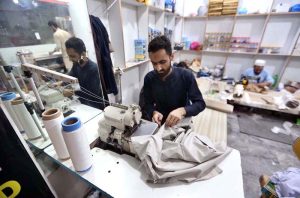 Tailor busy cutting and stitching clothes for customers at his workplace in connection with upcoming Eid-ul Fitr.
