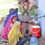 Gypsy girls are filling their pots with clean water from a tap in Husseinabad