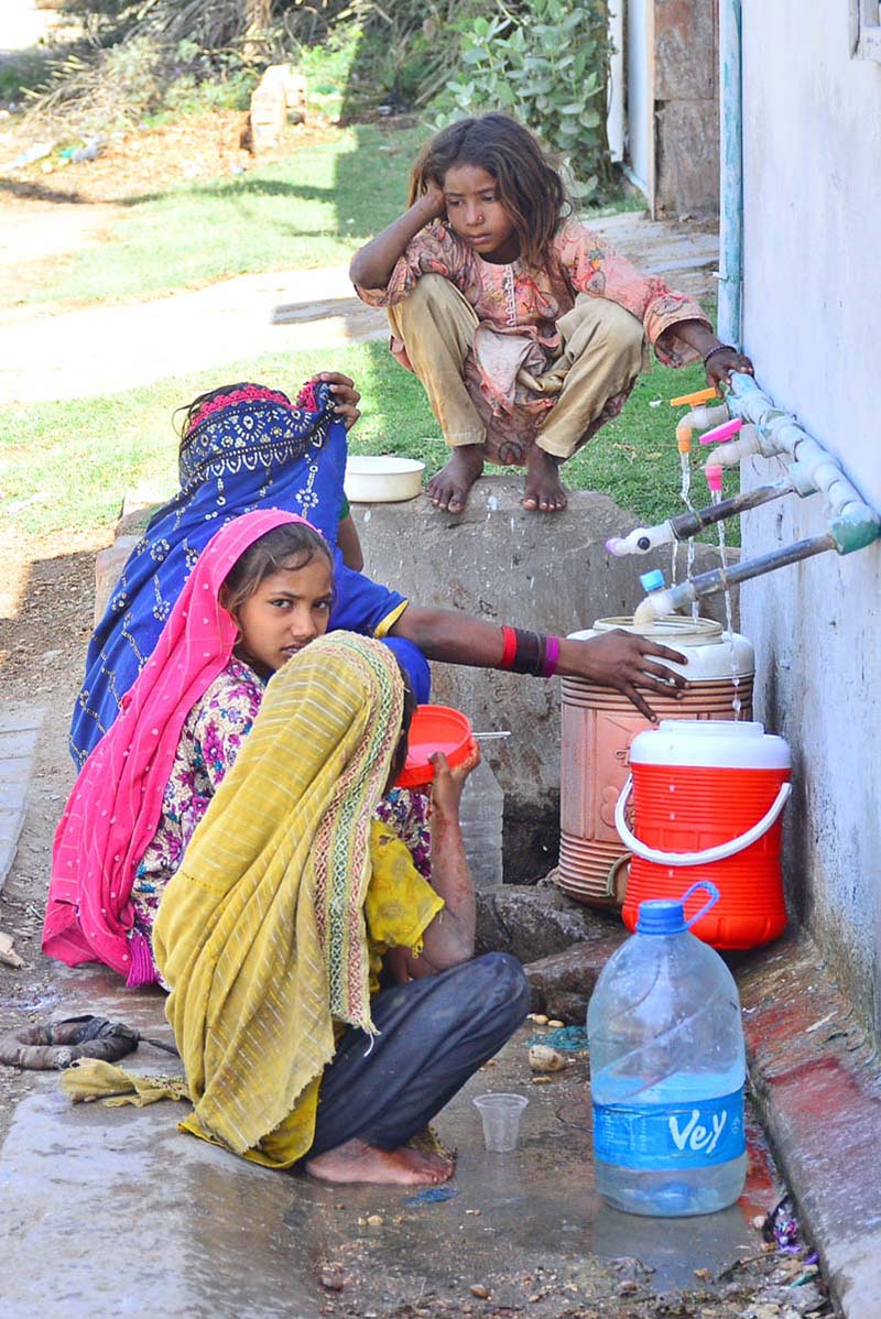 Gypsy girls are filling their pots with clean water from a tap in Husseinabad