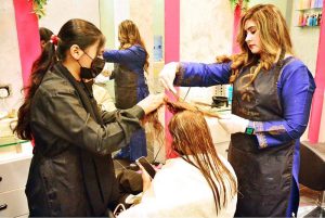 Beautician busy in applying hair color to female customer at local beauty salon in connection with upcoming Eidul Fitr