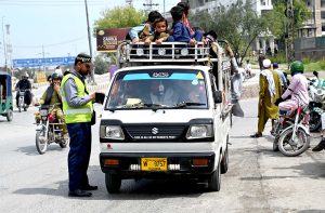 A traffic warden giving chalan to a driver due to overloading passengers at Central Jail road.