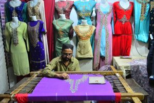 An artisan creates intricate beautiful embroidery designs on women's clothing at his workplace ahead of Eid-ul-Fitr.