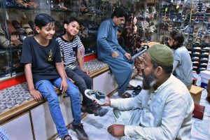 Youngsters selecting and purchasing sandals from vendor in connection with upcoming Eidul Fitr at Tilak Chari Road.
