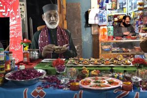 An elderly vendor prepares paan at his shop to attract customers at Banni Chowk in the city.