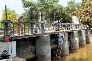 Workers busy carrying out repair and maintenance work on a canal regulator gate to ensure smooth water flow for irrigation during the ongoing season.