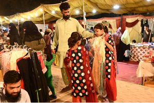 Women selecting and purchasing bangles from vendor shop at Latifabad market in connection with upcoming eidul fitr.