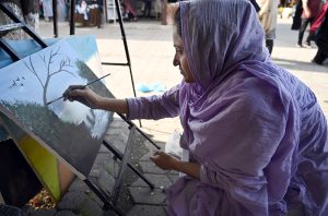 - A young female artist meticulously works on a landscape painting, showcasing her talent in public spaces. At H-9 Bazaar in the federal capital, creativity and artistry come alive for the community to enjoy.