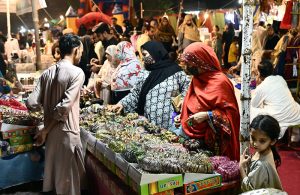 Women selecting and purchasing bangles from vendor shop at Latifabad market in connection with upcoming eidul fitr.