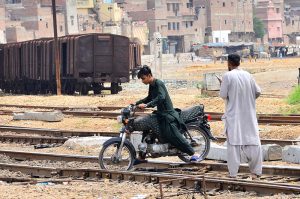 A view of motorcyclist crossing the rail track near railway station.