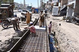 Labourers are busy construction work of nullah during development work at Autobahn Road.