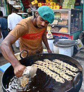 A vendor busy preparing traditional sweet item ‘jaleebi’ at his shop in a local market.