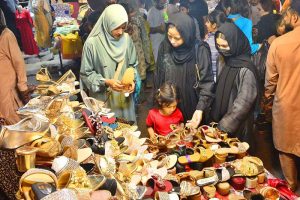 Women are busy selecting and purchasing shoes from stall at local market in connection with upcoming Eid ul Fitr