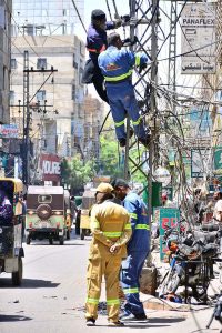 HESCO workers repair a wire on a pole at Haider Chowk to restore power supply in the area