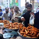 People busy purchasing traditional food items for iftar from a vendor stall at Latifabad Unit 11 during the holy month of Ramazan