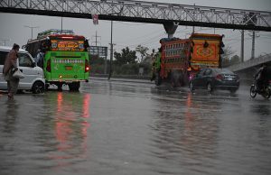 Vehicles passing through the stagnant water at IJP Road during rain in the Federal Capital.