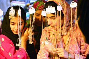 Women are busy selecting and purchasing shoes from stall at local market in connection with upcoming Eid ul Fitr