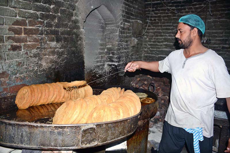 A vendor prepares traditional pheni (fried vermicelli) at his shop as demand increases ahead of Eidul Fitr