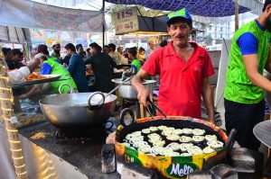 People busy purchasing traditional food items for iftar from a vendor stall at Latifabad Unit 11 during the holy month of Ramazan