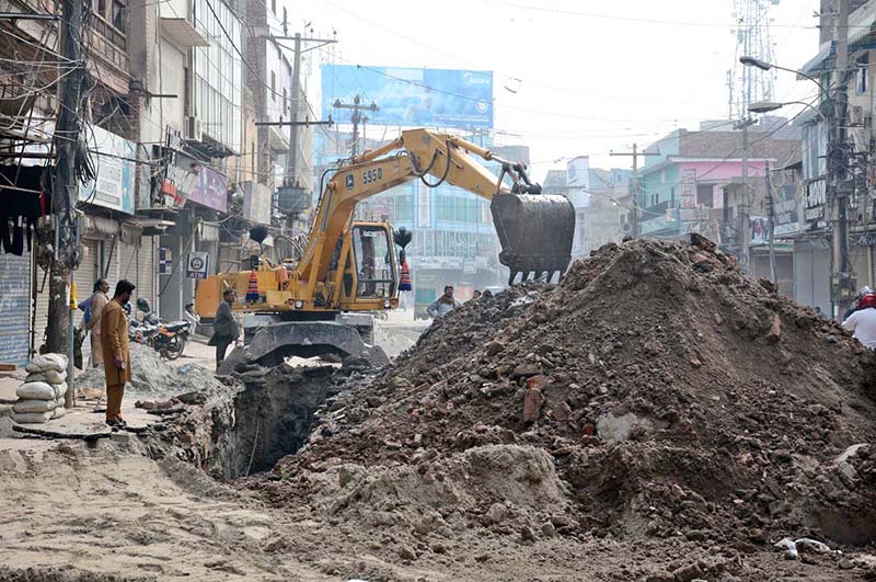 Workers are busy digging to lay a sewage pipeline with the help of machinery in the Hussain Agahi area