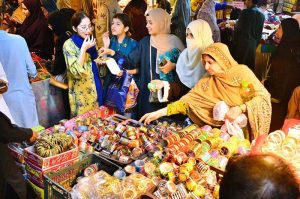 Women are busy selecting and purchasing shoes from stall at local market in connection with upcoming Eid ul Fitr