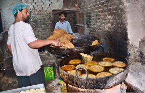 A vendor prepares traditional pheni (fried vermicelli) at his shop as demand increases ahead of Eidul Fitr