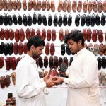 A man is busy purchasing shoes for the upcoming Eid-ul Fitr at Resham Gali