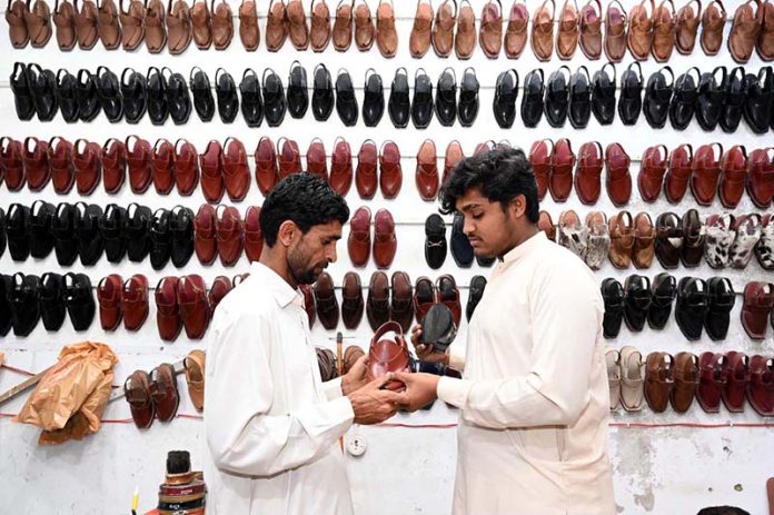 A man is busy purchasing shoes for the upcoming Eid-ul Fitr at Resham Gali