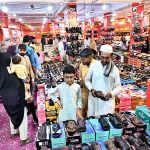 People are busy purchasing shoes and sandals from a vendor stall for the upcoming Eid-ul-Fitr in Unit No. 8, Latifabad
