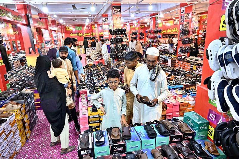 People are busy purchasing shoes and sandals from a vendor stall for the upcoming Eid-ul-Fitr in Unit No. 8, Latifabad