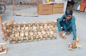 A worker busy in making wooden toy at his setup.