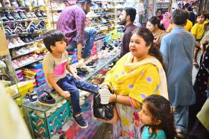Women are busy selecting and purchasing shoes from stall at local market in connection with upcoming Eid ul Fitr
