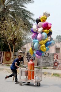 Struggling for livelihood. A disable street vendor on his way to sell air filled toys.