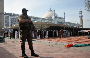 A security official stands on high alert as a large number of faithful offer the fourth Namaz-e-Juma (Friday prayer) during the holy month of Ramazan at Eidgah Masjid amid strict security arrangements.