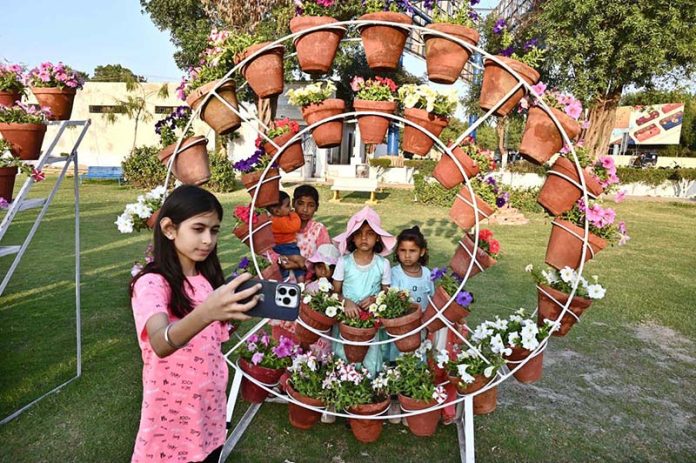A girl taking selfie with call phone during 22nd Annual Garden Competition & Spring Flower Show 2026 organized by Cantonment Board Hyderabad at Lt. Col. Hassan (Shaheed) Family Park, Qasim Chowk