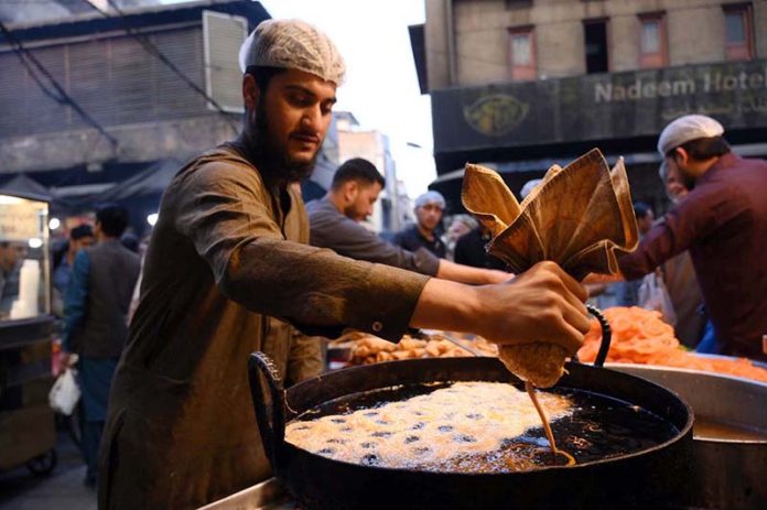 A vendor busy in preparing traditional sweet item jalebi for the customers at Fawara Chowk