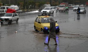 Vehicles passing through the stagnant water at IJP Road during rain in the Federal Capital.