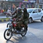 Women police personnel ride a motorcycle along University Road on their way to the office to maintain law and order during the holy month of Ramazan.