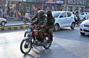 Women police personnel ride a motorcycle along University Road on their way to the office to maintain law and order during the holy month of Ramazan.