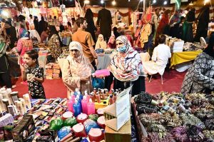 People are busy purchasing shoes and sandals from a vendor stall for the upcoming Eid-ul-Fitr in Unit No. 8, Latifabad