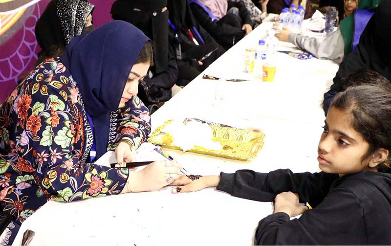 A girl being decorated her hand with Hinna (Mehndi) during the Eid Free Bazaar “Maa Hum Bhi Eid Manyen Gay” organized by JDC Welfare Foundation