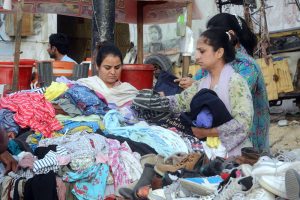 Women select second-hand clothes from a roadside stall in Saddar.