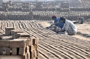 Labourers prepare and arrange freshly molded clay bricks at a brick kiln on the outskirts of the city.