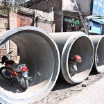 Citizens park their motorcycles inside large sewerage pipes placed along a roadside at Muslim Bazaar.