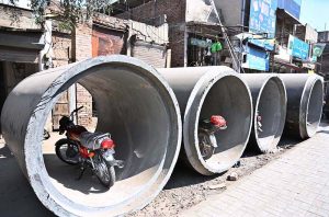 Citizens park their motorcycles inside large sewerage pipes placed along a roadside at Muslim Bazaar.