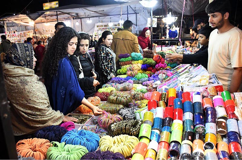 Women busy selecting and purchasing bangles from a stall at Jinnah Super Market ahead of Eid-ul-Fitr in the Federal Capital