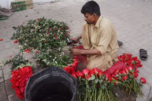 A vendor prepares a fresh flower bouquet at a roadside stall.