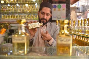 A vendor fills small rolling bottles while selling a variety of perfumes and fragrances at Hashtnagri area