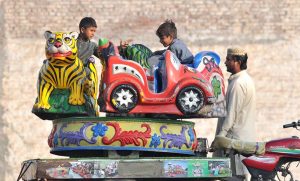 Children have fun on a swing set along the roadside, enjoying the playful moment.