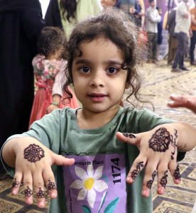 A girl being decorated her hand with Hinna (Mehndi) during the Eid Free Bazaar “Maa Hum Bhi Eid Manyen Gay” organized by JDC Welfare Foundation
